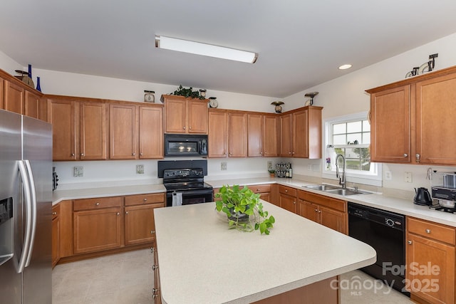kitchen featuring brown cabinets, a sink, light countertops, a center island, and black appliances