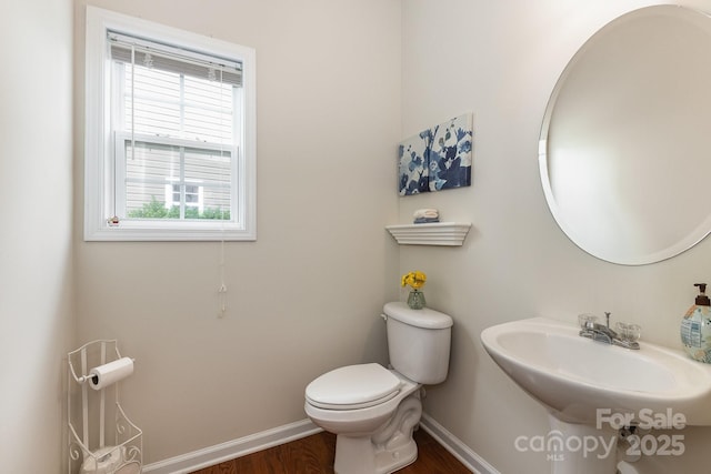 bathroom with toilet, baseboards, and a wealth of natural light