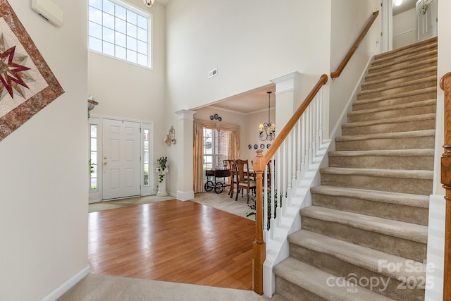 entryway featuring an inviting chandelier, stairs, baseboards, wood finished floors, and a towering ceiling