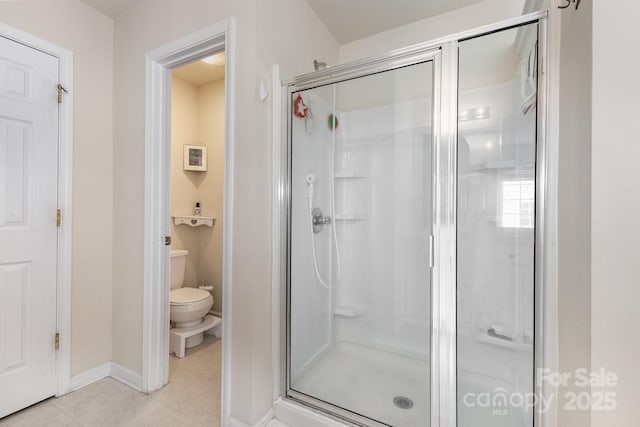 full bathroom featuring toilet, baseboards, tile patterned flooring, and a stall shower