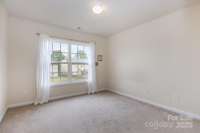 carpeted spare room featuring baseboards and visible vents
