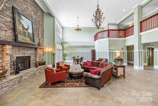 living room with recessed lighting, a stone fireplace, and a towering ceiling