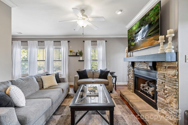 living area featuring baseboards, wood finished floors, ceiling fan, a fireplace, and ornamental molding