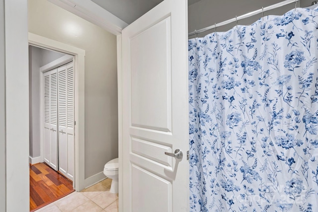 full bath with curtained shower, toilet, baseboards, and tile patterned floors