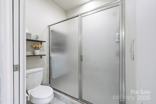 full bath with toilet, tile patterned flooring, and a stall shower