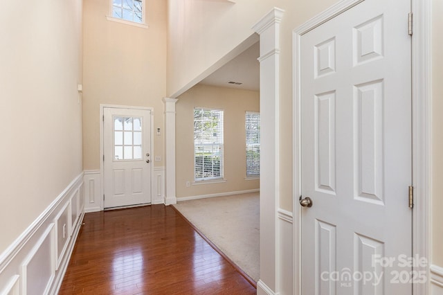 foyer entrance with decorative columns and dark wood-style flooring