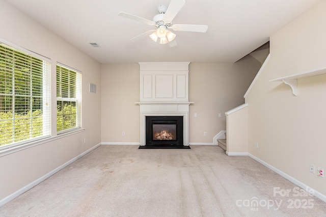 unfurnished living room featuring visible vents, light colored carpet, a fireplace, stairs, and ceiling fan