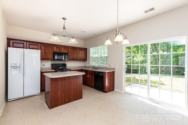 kitchen with a sink, visible vents, light countertops, a kitchen island, and black appliances