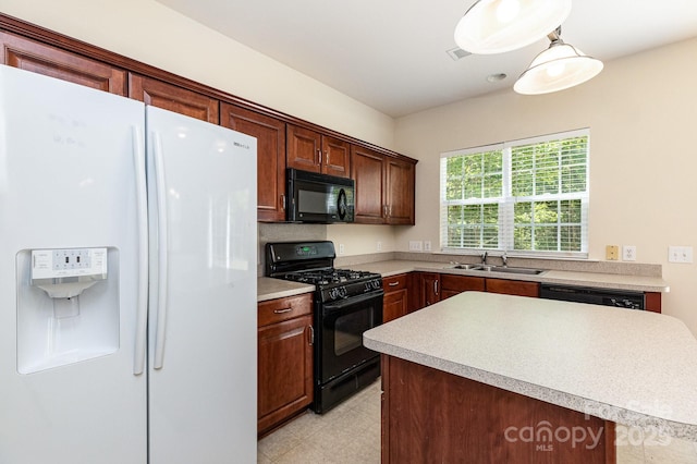 kitchen featuring light floors, light countertops, a sink, black appliances, and hanging light fixtures