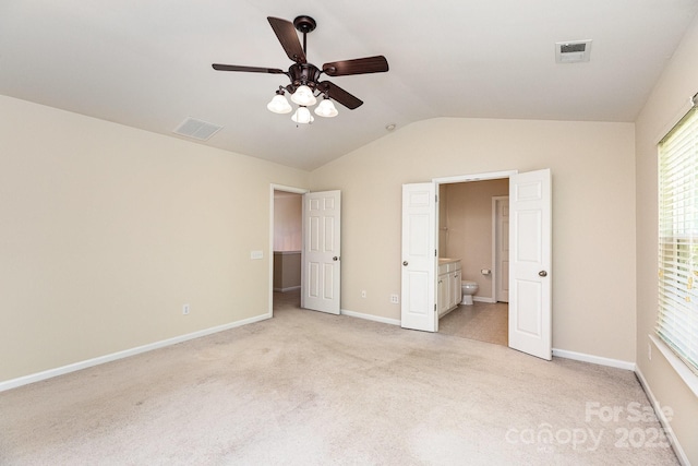 unfurnished bedroom with connected bathroom, light carpet, vaulted ceiling, and visible vents