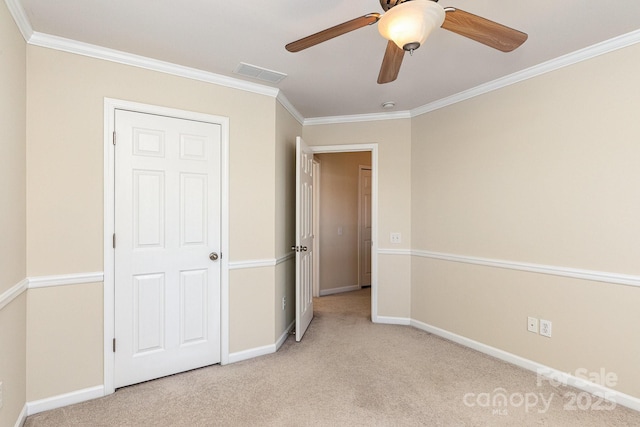 unfurnished bedroom with carpet flooring, baseboards, visible vents, ceiling fan, and ornamental molding