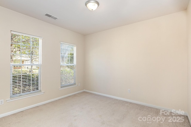 spare room with baseboards, visible vents, and light colored carpet