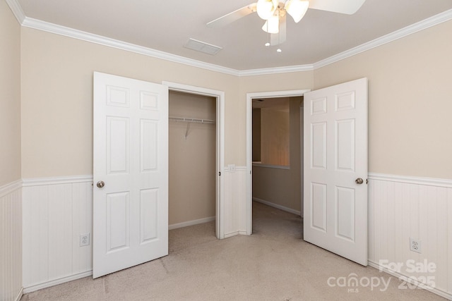 unfurnished bedroom featuring carpet, a closet, a wainscoted wall, and ornamental molding