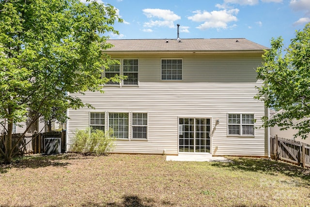back of house featuring a lawn, a fenced backyard, and roof with shingles