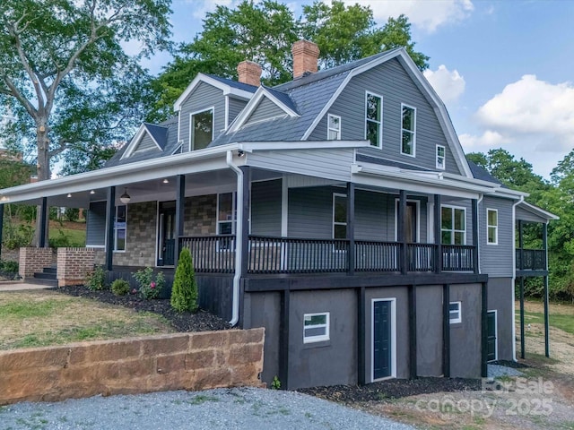 view of front of home featuring a chimney, a gambrel roof, and covered porch