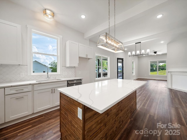 kitchen with open floor plan, dishwasher, a sink, dark wood-style floors, and beam ceiling