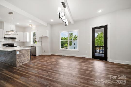 kitchen featuring dark wood-type flooring, stove, light countertops, baseboards, and white cabinets