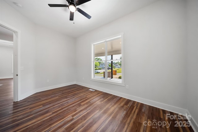 unfurnished room with dark wood-style floors, a ceiling fan, baseboards, and a smoke detector