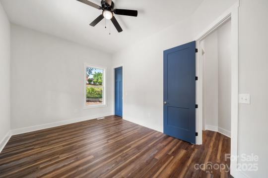empty room with dark wood finished floors, ceiling fan, and baseboards