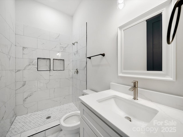 full bathroom with toilet, tiled shower, vanity, and marble look tile flooring