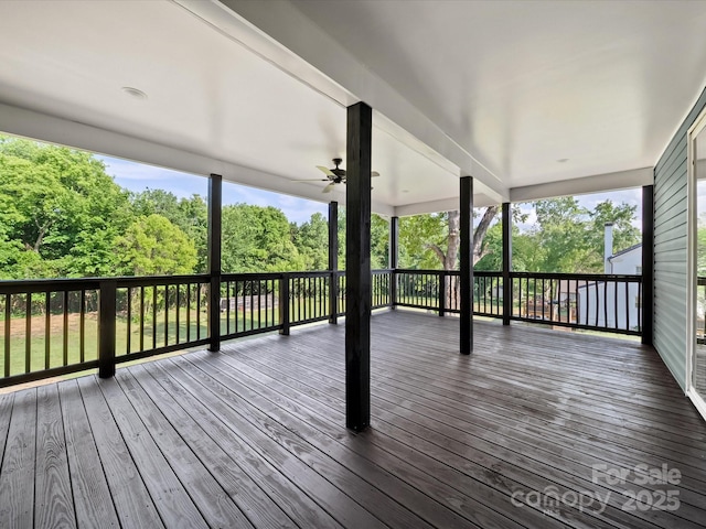 deck featuring ceiling fan and view of wooded area