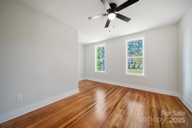 spare room featuring light wood finished floors, baseboards, and ceiling fan