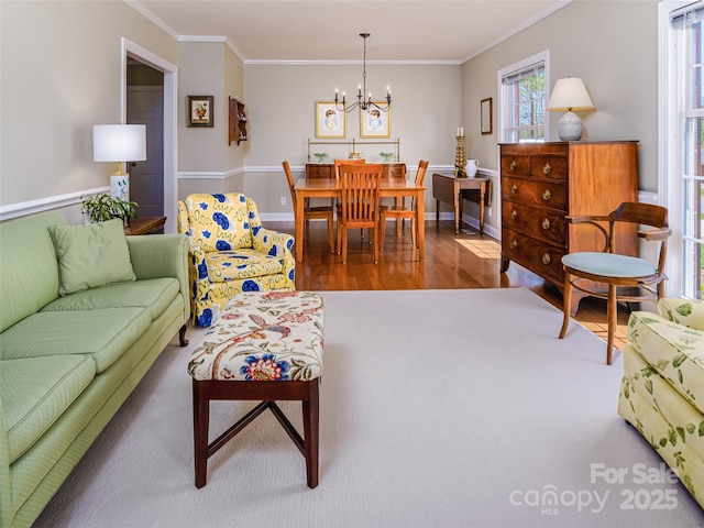 living room featuring a chandelier, ornamental molding, wood finished floors, and baseboards