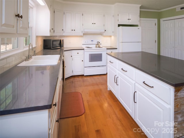 kitchen featuring white appliances, under cabinet range hood, a sink, dark countertops, and ornamental molding