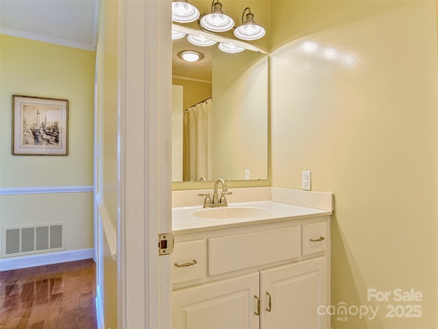 bathroom with ornamental molding, wood finished floors, vanity, and baseboards
