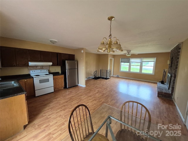 kitchen with light wood finished floors, under cabinet range hood, freestanding refrigerator, and electric range