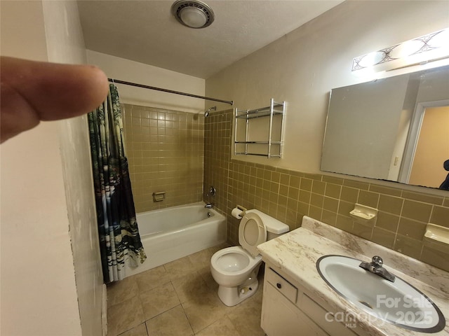 bathroom featuring tile patterned floors, vanity, tile walls, toilet, and shower / bath combo with shower curtain