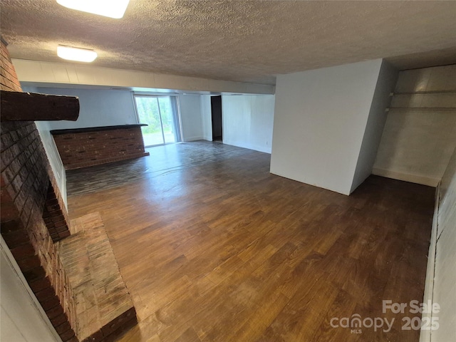 unfurnished living room featuring a textured ceiling and dark wood-style flooring