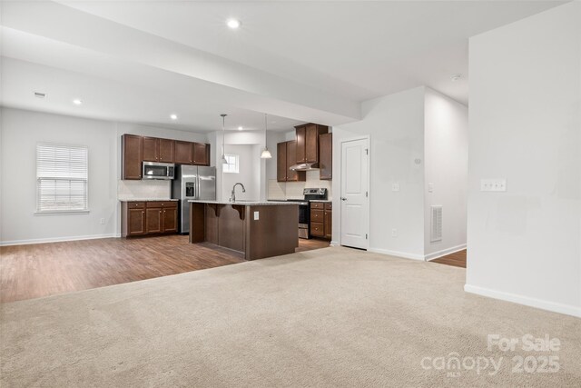 1933 Tin Roof Ln, Monroe, NC 28112 - kitchen featuring a sink, light carpet, baseboards, appliances with stainless steel finishes, and open floor plan
