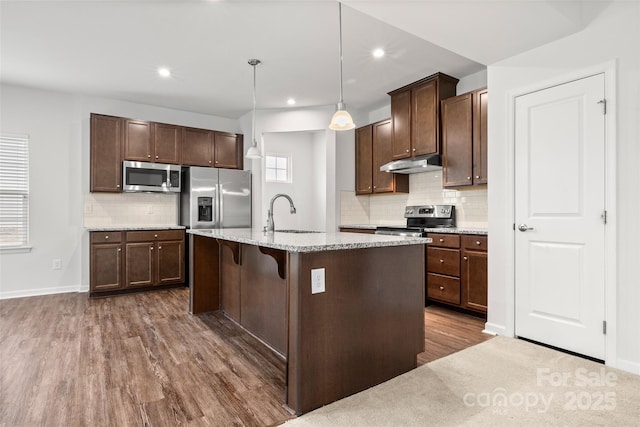 1933 Tin Roof Ln, Monroe, NC 28112 - kitchen with under cabinet range hood, appliances with stainless steel finishes, backsplash, a sink, and dark wood-style floors