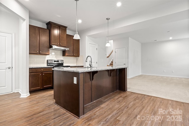 1933 Tin Roof Ln, Monroe, NC 28112 - kitchen featuring dark brown cabinetry, baseboards, under cabinet range hood, a kitchen bar, and electric stove