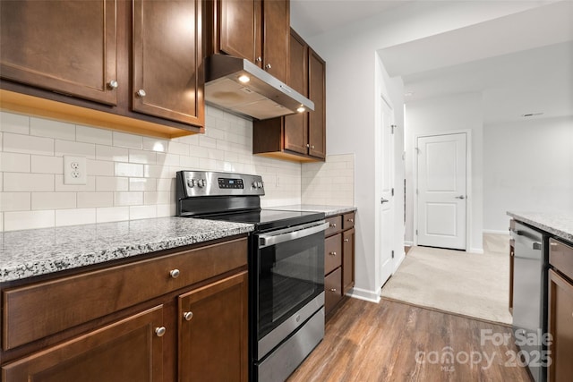 1933 Tin Roof Ln, Monroe, NC 28112 - kitchen with under cabinet range hood, appliances with stainless steel finishes, backsplash, dark wood-style flooring, and baseboards