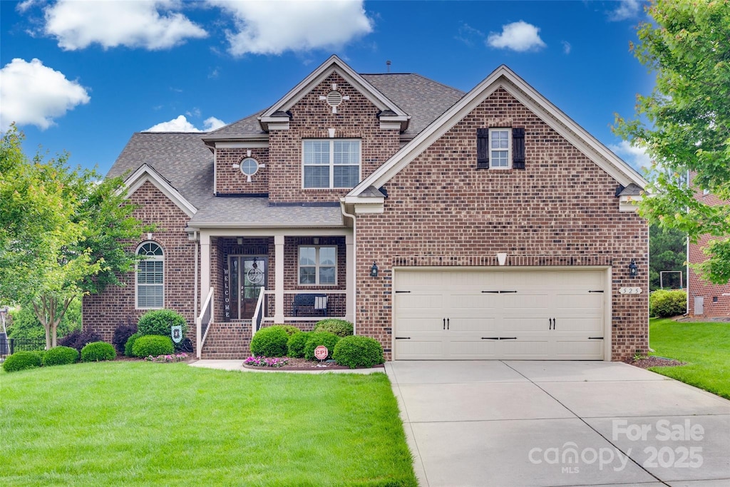 525 Chase Prairie Ln, Waxhaw, NC 28173 - traditional-style home with brick siding, a front yard, driveway, a shingled roof, and a garage