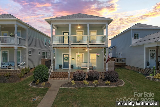 view of front of property with covered porch, ceiling fan, a front yard, and a balcony