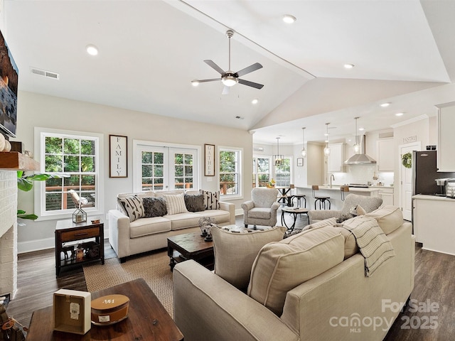 living room featuring a healthy amount of sunlight, visible vents, lofted ceiling, ceiling fan, and dark wood-type flooring