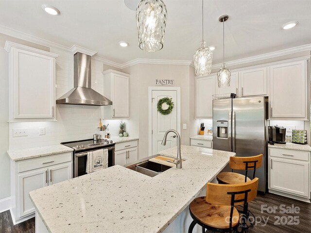 kitchen featuring a sink, appliances with stainless steel finishes, wall chimney exhaust hood, ornamental molding, and dark wood-style floors