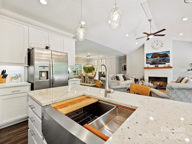 kitchen with a large fireplace, open floor plan, ceiling fan, and stainless steel fridge with ice dispenser