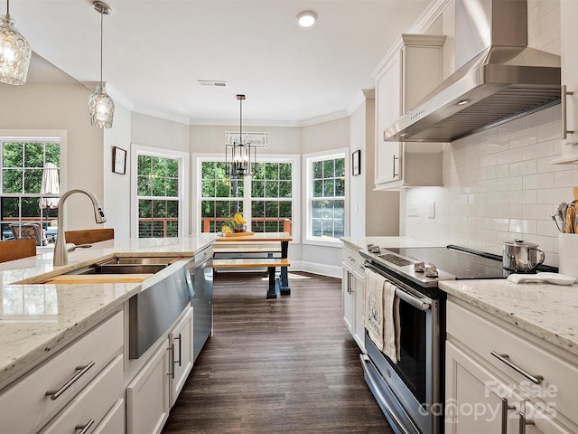 kitchen with backsplash, wall chimney range hood, dark wood-type flooring, pendant lighting, and appliances with stainless steel finishes