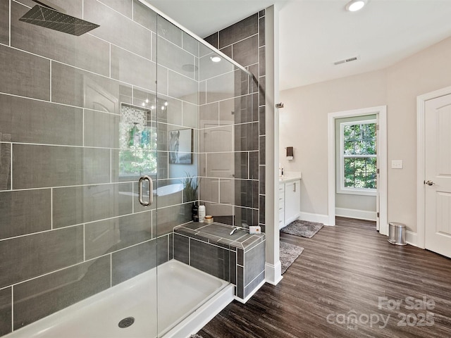 bathroom featuring a shower stall, wood finished floors, vanity, baseboards, and visible vents
