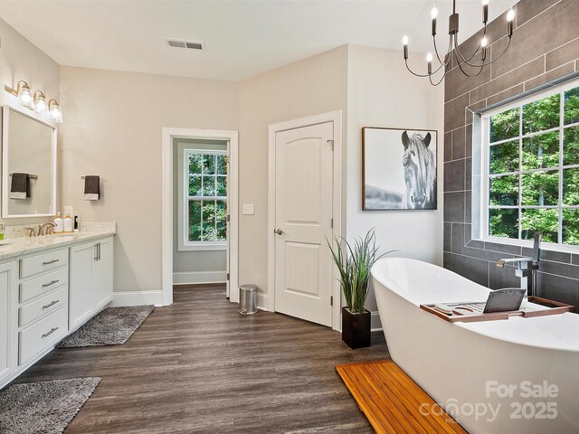 bathroom featuring a freestanding bath, wood finished floors, visible vents, and vanity