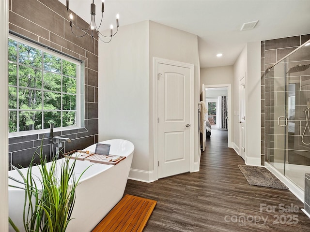 bathroom featuring a freestanding bath, a shower stall, baseboards, and wood finished floors
