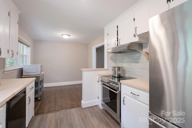 4920 Raymond Pl, Charlotte, NC 28205 - kitchen with appliances with stainless steel finishes, under cabinet range hood, tasteful backsplash, wood finished floors, and light countertops
