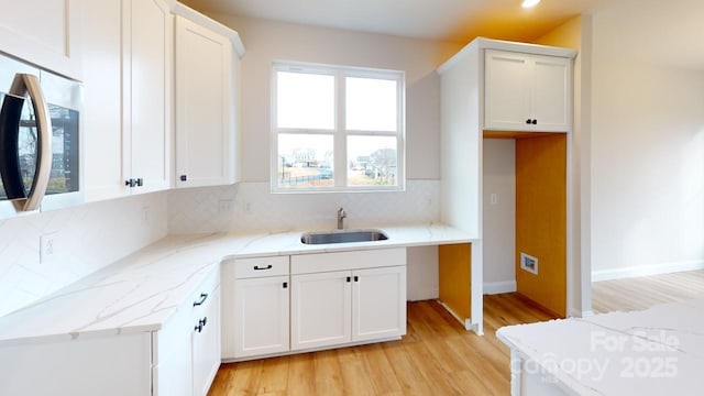606 Banter Ln Unit 30, Cramerton, NC 28032 - kitchen with stainless steel microwave, light wood finished floors, tasteful backsplash, white cabinets, and recessed lighting