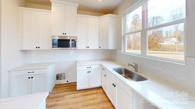 606 Banter Ln Unit 30, Cramerton, NC 28032 - kitchen with stainless steel microwave, light stone countertops, tasteful backsplash, and light wood-style flooring