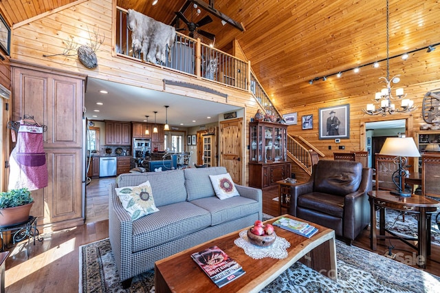 living room with high vaulted ceiling, track lighting, an inviting chandelier, wooden ceiling, and wood walls
