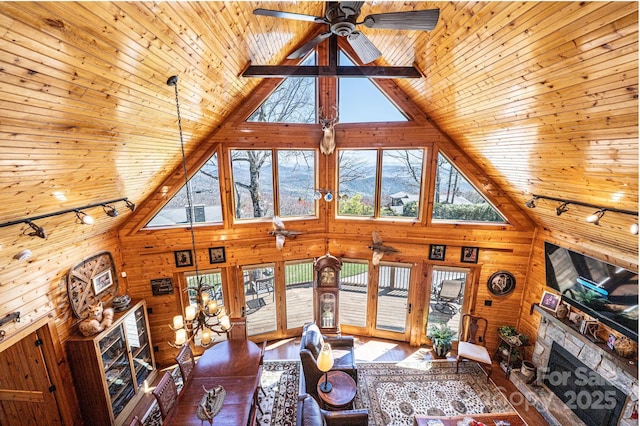 living area with wooden walls, rail lighting, wooden ceiling, a fireplace, and high vaulted ceiling